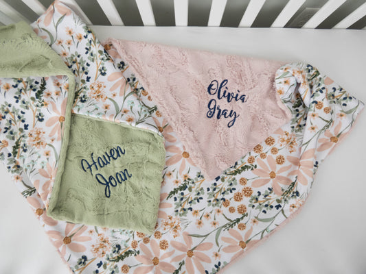 Floral baby blanket with embroidered names on a crib